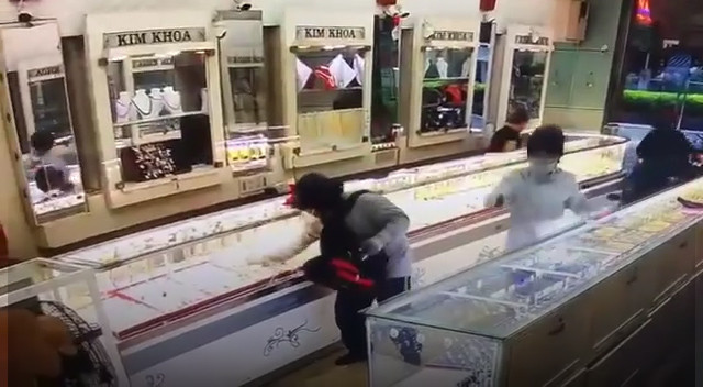 Hai nghi phạm dùng súng uy hiếp bảo vệ để thực hiện vụ cướp. Ảnh cắt từ clip. Hai nghi phạm dùng súng uy hiếp bảo vệ để thực hiện vụ cướp. Ảnh cắt từ clip.