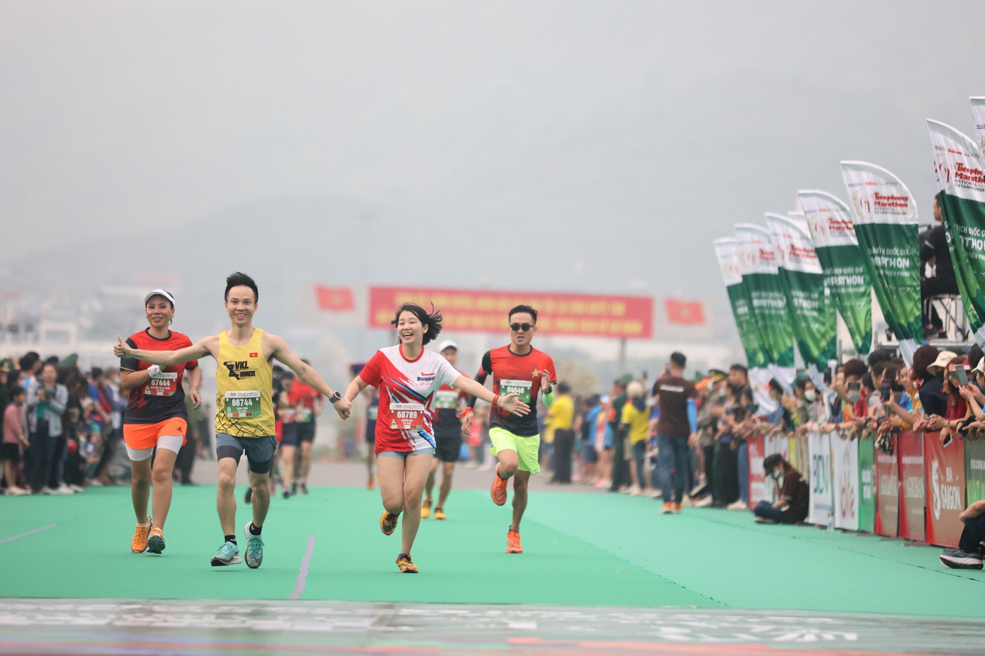 Nhà báo Quỳnh Nga nắm tay ông xã cán đích cự ly 10km. Ảnh: Như Ý.