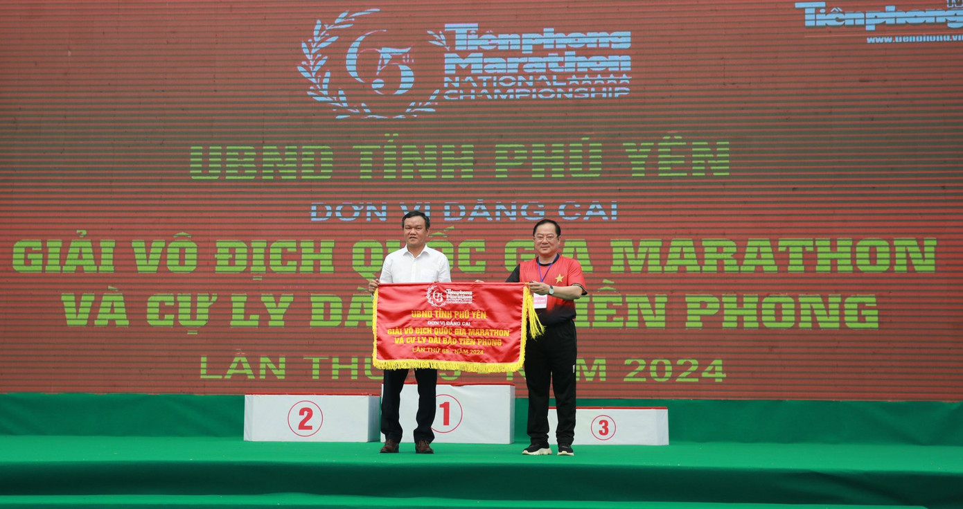 Nhà báo Lê Xuân Sơn - Tổng Biên tập báo Tiền Phong trao cờ đăng cai giải Vô địch quốc gia Marathon và cự ly dài báo Tiền Phong lần thứ 65 - năm 2024 tới Phó Chủ tịch UBND tỉnh Phú Yên Đào Mỹ.