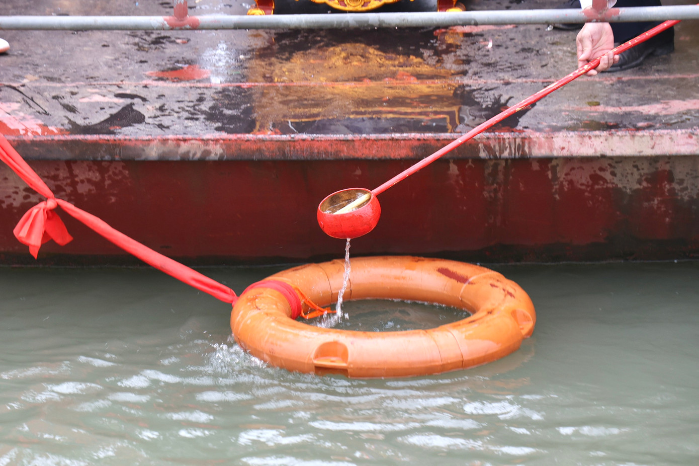 Hàng chục gáo nước được lấy tại khu vực giữa sông Hồng đổ vào bình để đem về lễ.