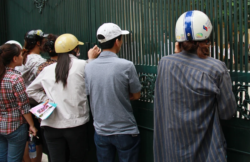 Nhiều người ghé sát vào cổng trường chờ đợi con em mình. Ảnh: Trường Phong