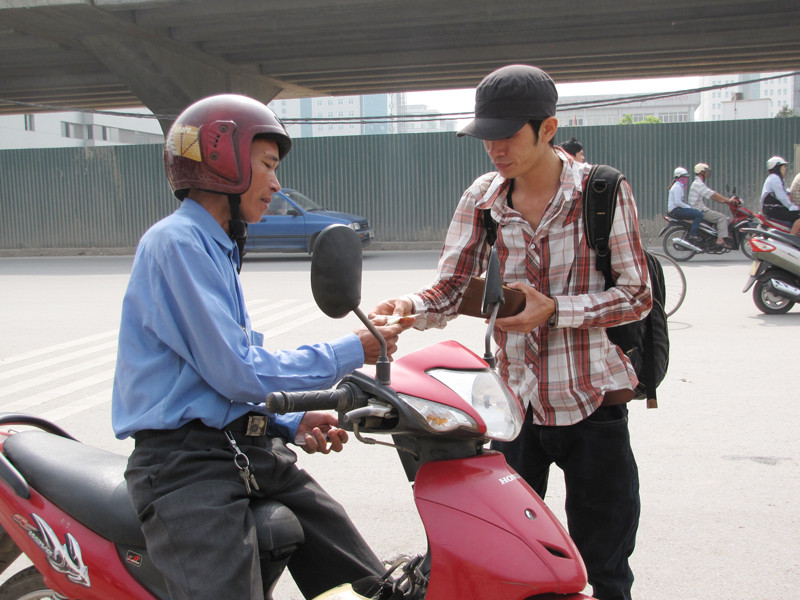 Một sinh viên vội vàng trả tiền xe ôm để kịp vào bắt xe