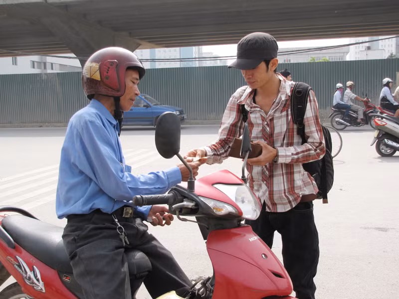 Một sinh viên vội vàng trả tiền xe ôm để kịp vào bắt xe