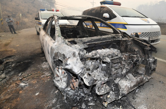 Cảnh sát xem xét một chiếc xe đã cháy rụi của người dân tại huyện Yeongdeok (tỉnh Gyeongsang Bắc) vào ngày 26/3. Ảnh: News1.