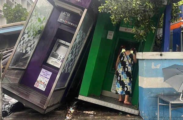 Người phụ nữ vào cây ATM để thực hiện giao dịch dù cây ATM bị nghiêng do mưa dông. Ảnh: Fo UR).