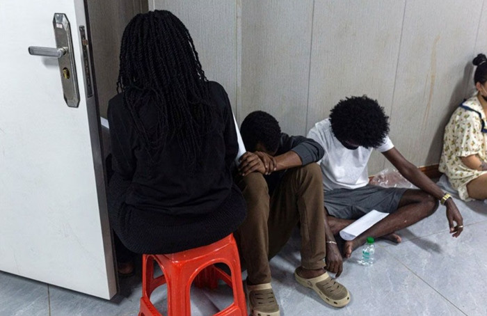 Đây được cho là những người làm việc trong các trung tâm lừa đảo đang ngồi nghỉ trong một vụ truy quét lừa đảo ở Myanmar. Ảnh: AFP.