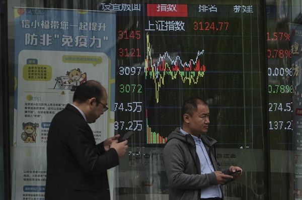 Vài người đi ngang qua một bảng điện tử hiển thị các chỉ số giao dịch cổ phiếu ở Bắc Kinh (Trung Quốc). Ảnh chụp ngày 8/4. Ảnh: Andy Wong/ AP.