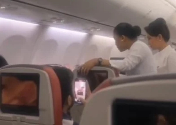 Tiếp viên cố thuyết phục nữ hành khách (không nhìn rõ trong ảnh) cài dây an toàn vì "việc này không chỉ cho cô, mà còn cho con của cô nữa". Ảnh: Jam Press.