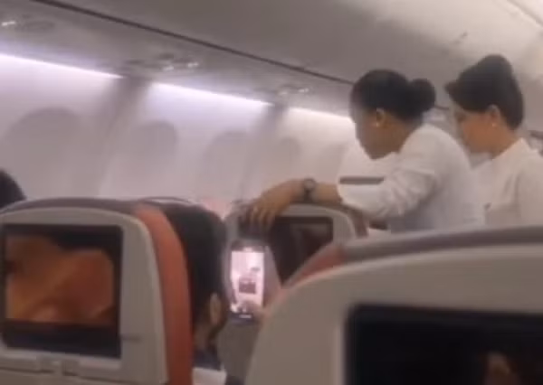 Tiếp viên cố thuyết phục nữ hành khách (không nhìn rõ trong ảnh) cài dây an toàn vì "việc này không chỉ cho cô, mà còn cho con của cô nữa". Ảnh: Jam Press.