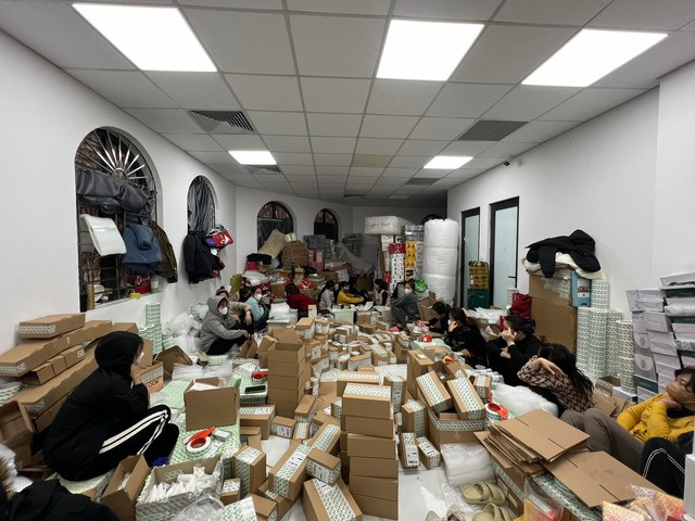 Hàng chục nhân viên đang đóng gói hàng để chuyển đi bên trong kho.