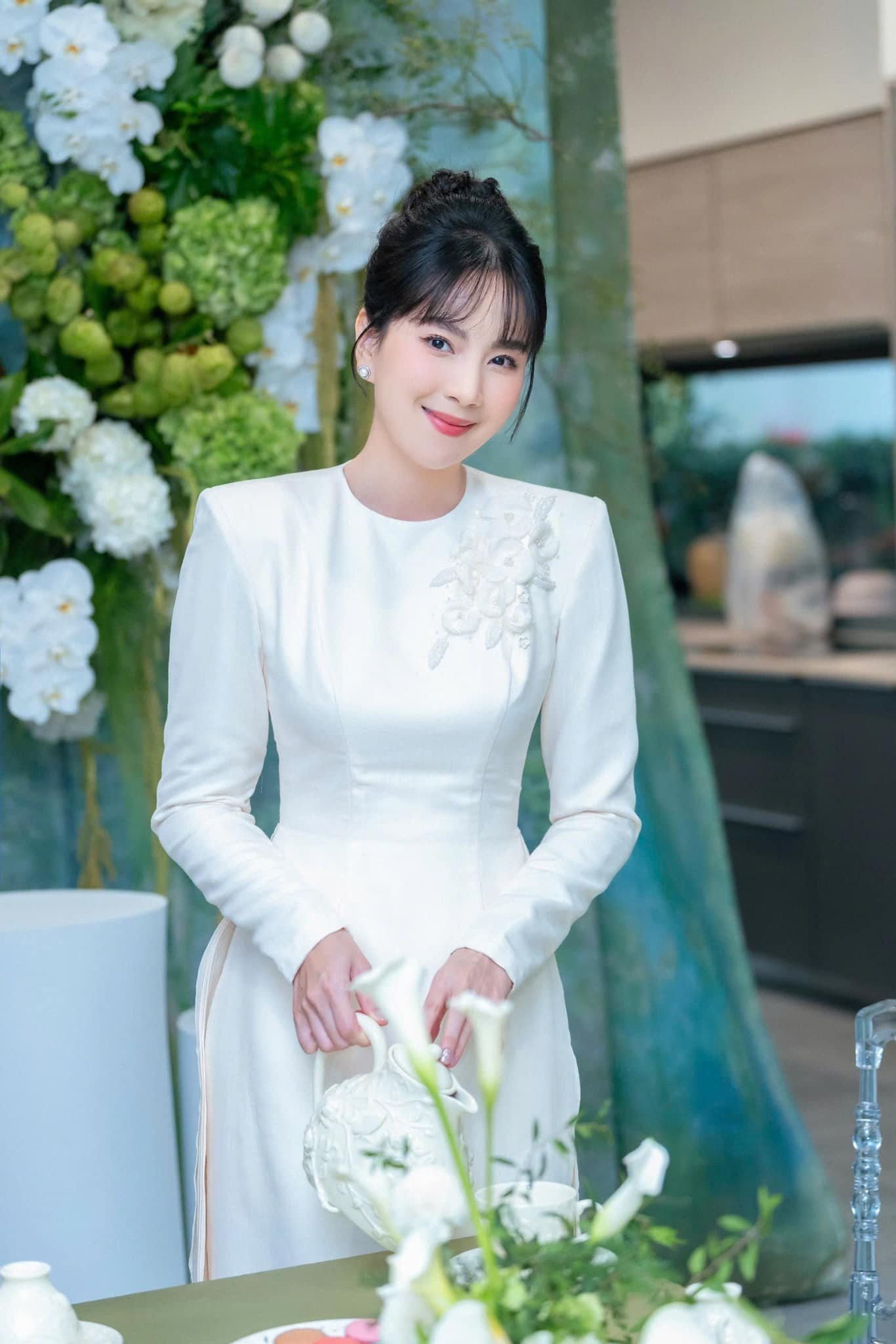 Trong lễ dạm ngõ, Mai Ngọc diện bộ áo dài trắng độn cầu vai thêu hoa mai thanh lịch, nền nã. Người đẹp búi tóc, trang điểm tông nude nhẹ nhàng. Nữ MC nhận nhiều lời khen về ngoại hình.