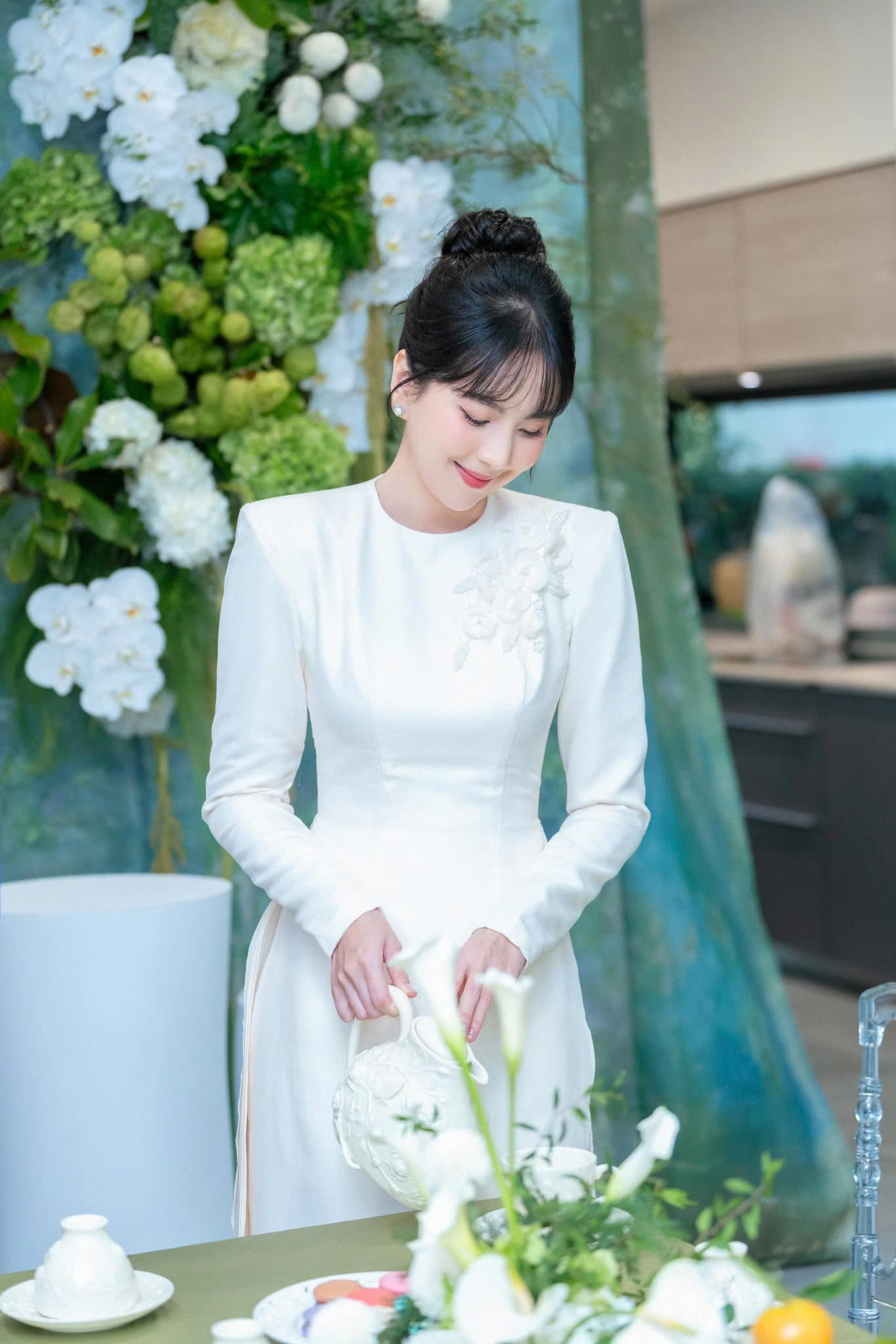 Trong lễ dạm ngõ, Mai Ngọc diện bộ áo dài trắng độn cầu vai thêu hoa mai thanh lịch, nền nã. Người đẹp búi tóc, trang điểm tông nude nhẹ nhàng. Nữ MC nhận nhiều lời khen về ngoại hình.