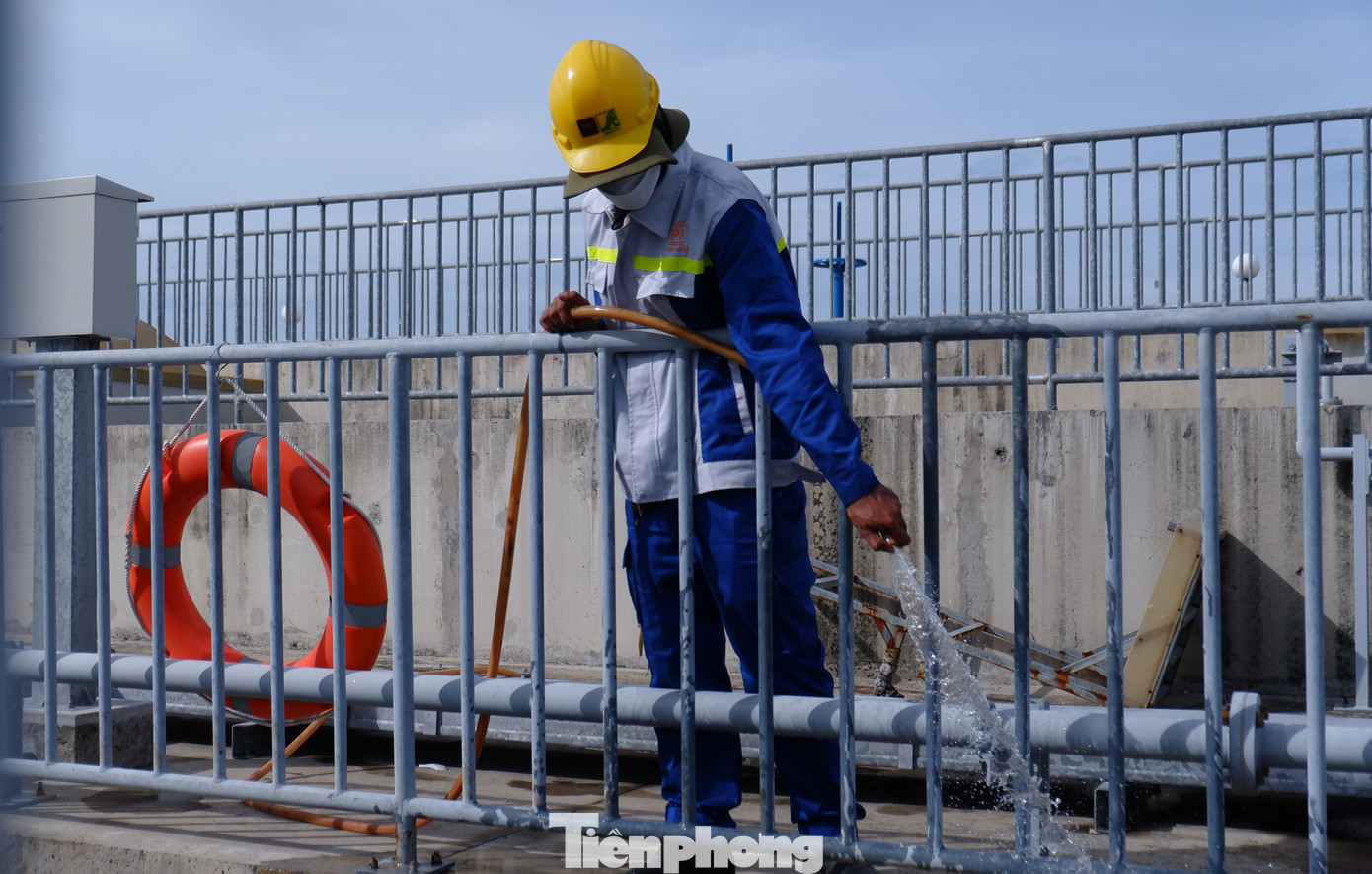 Công nhân tiến hành phun nước, rửa váng dầu ở bể lọc.