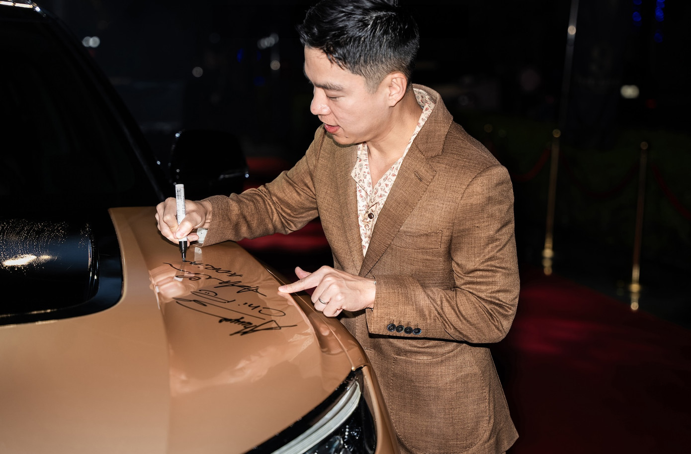 Nhà thiết kế Adrian Anh Tuấn ký tên lưu niệm trên chiếc VF 9. Anh tới sự kiện cùng doanh nhân Sơn Đoàn.