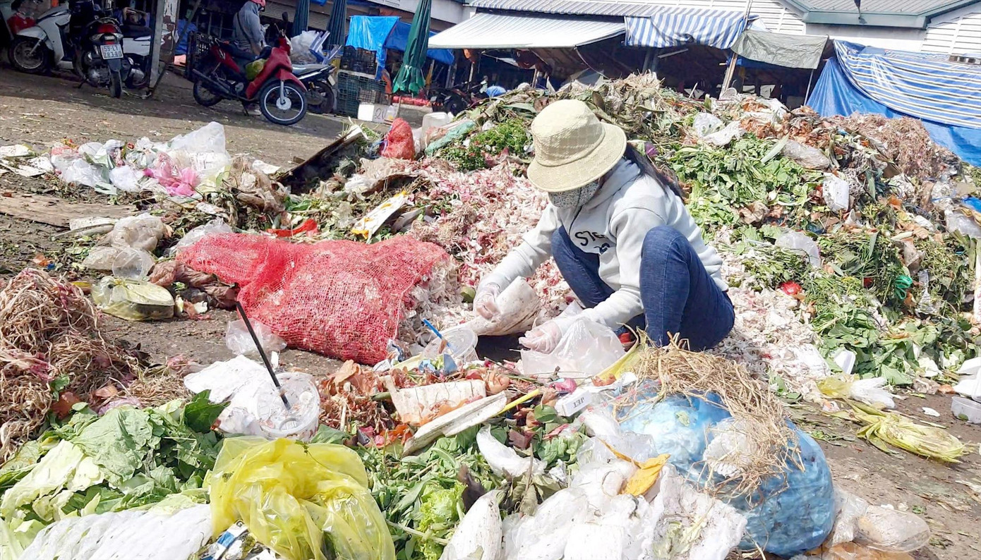 Một người phụ nữ nhặt nhạnh rau phế phẩm tại bãi rác trong chợ ĐMNS Thủ Đức. Ảnh: Thuận Nhàn