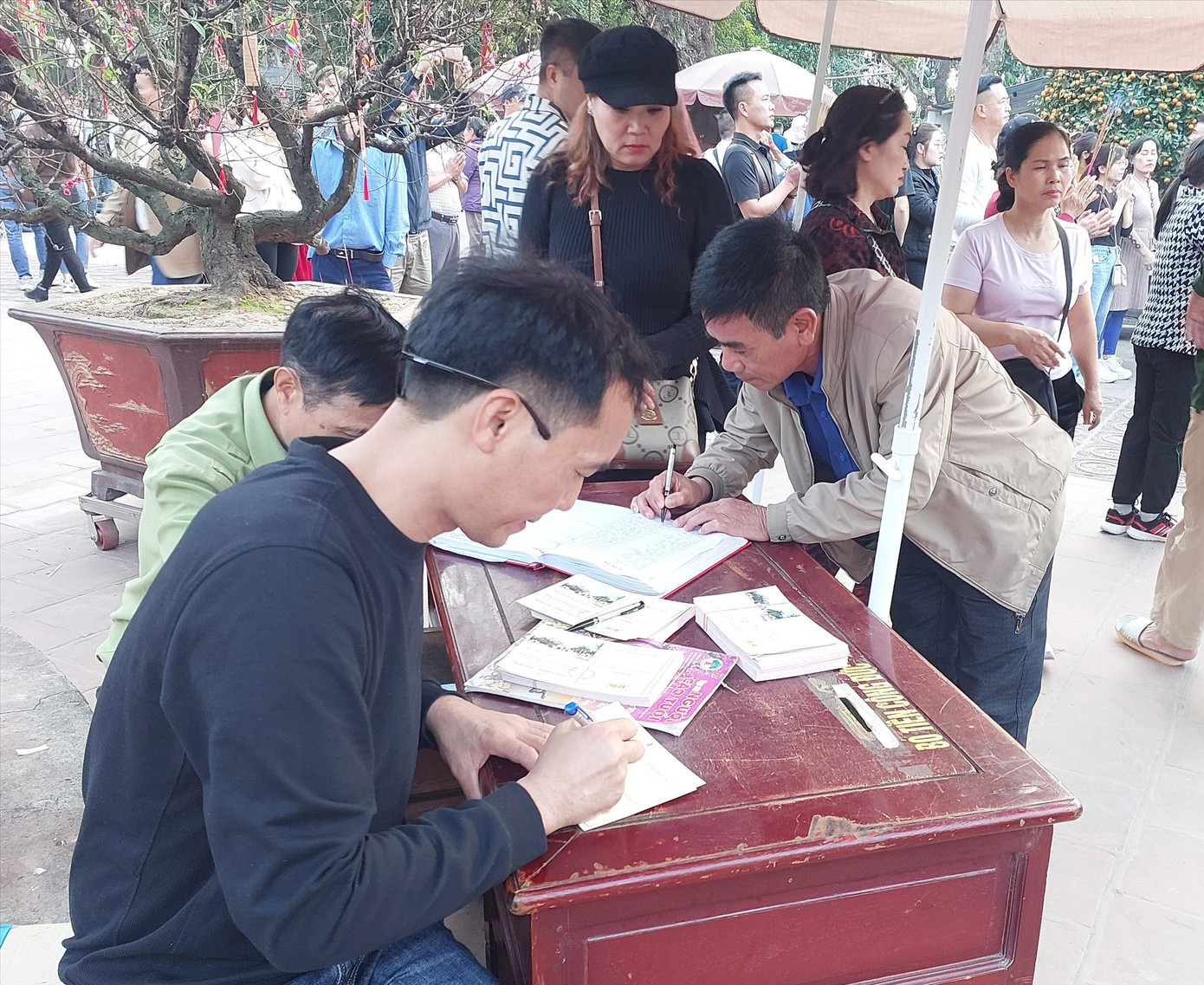 Người dân viết phiếu công đức tại Đền Trần (Nam Định). Ảnh: QN Người dân viết phiếu công đức tại Đền Trần (Nam Định). Ảnh: QN