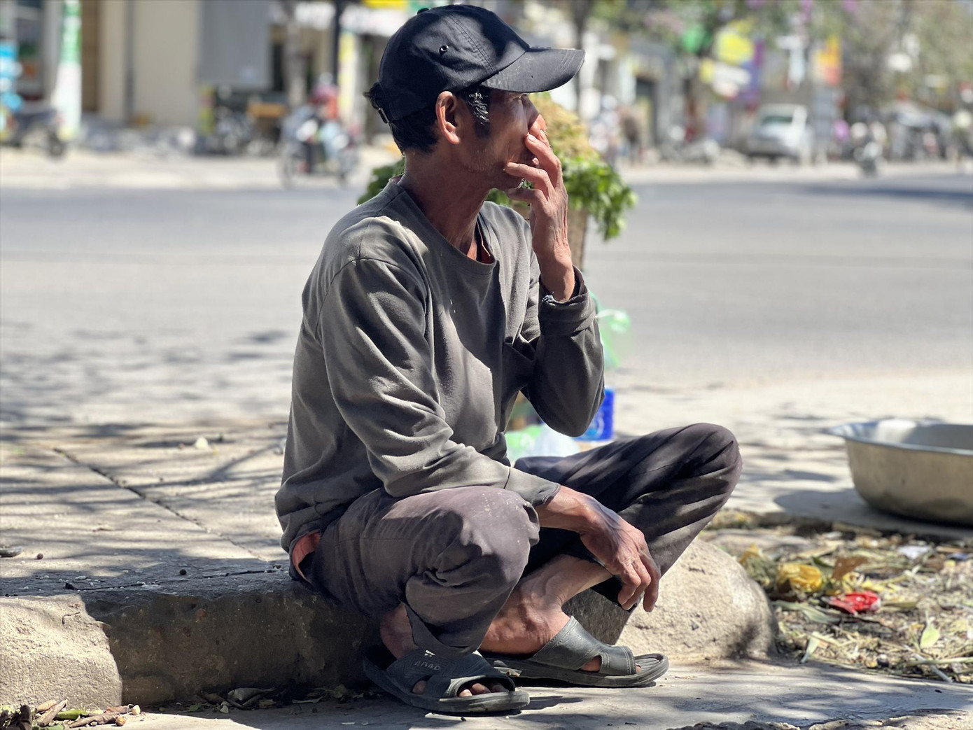 Ông A Riu ngồi bên vệ đường chờ người thuê bốc vác