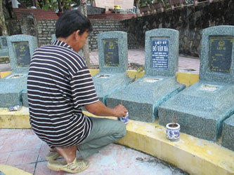 Quản trang Lê Tắc Quyết bên một ngôi mộ vô danh vừa được gắn bia. Ảnh: HM