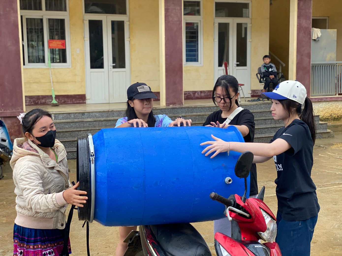 Thành viên dự án hỗ trợ vận chuyển nước sạch về nhà dân.