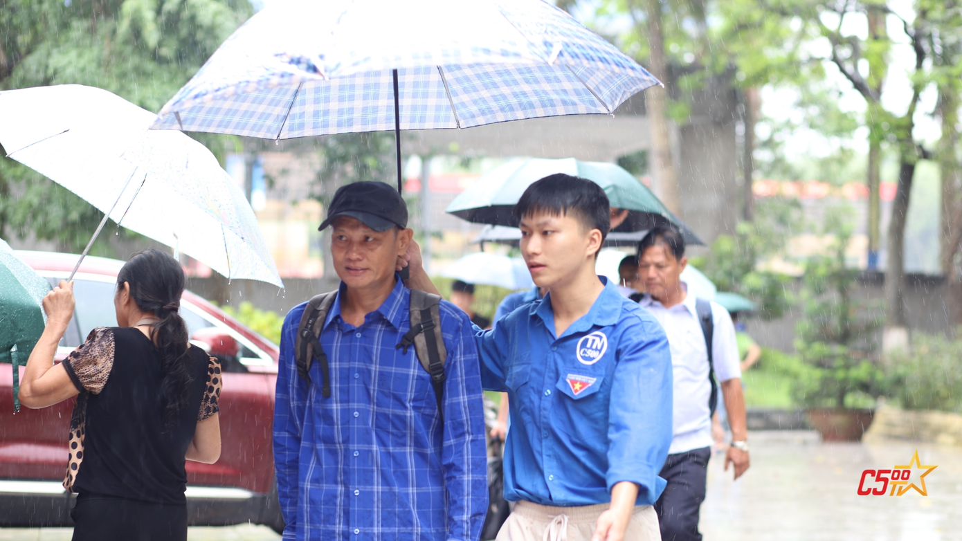 Đội tình nguyện hỗ trợ hướng dẫn tân sinh viên và phụ huynh đến địa điểm buổi lễ khi thời tiết không thuận lợi.
