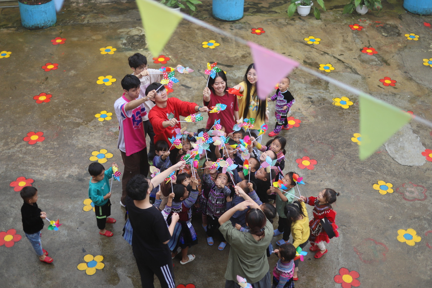 Khoảnh khắc thành viên dự án cùng các em nhỏ vui đùa dưới sân trường sau bữa ăn.