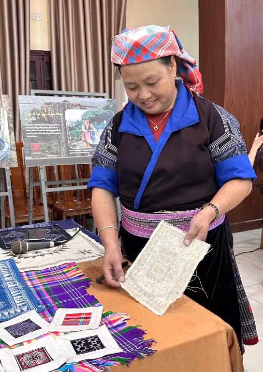 Chị Lý Thị Ninh bên cạnh một tác phẩm được vẽ hoa văn sáp ong trước khi đi đến công đoạn nhuộm chàm.