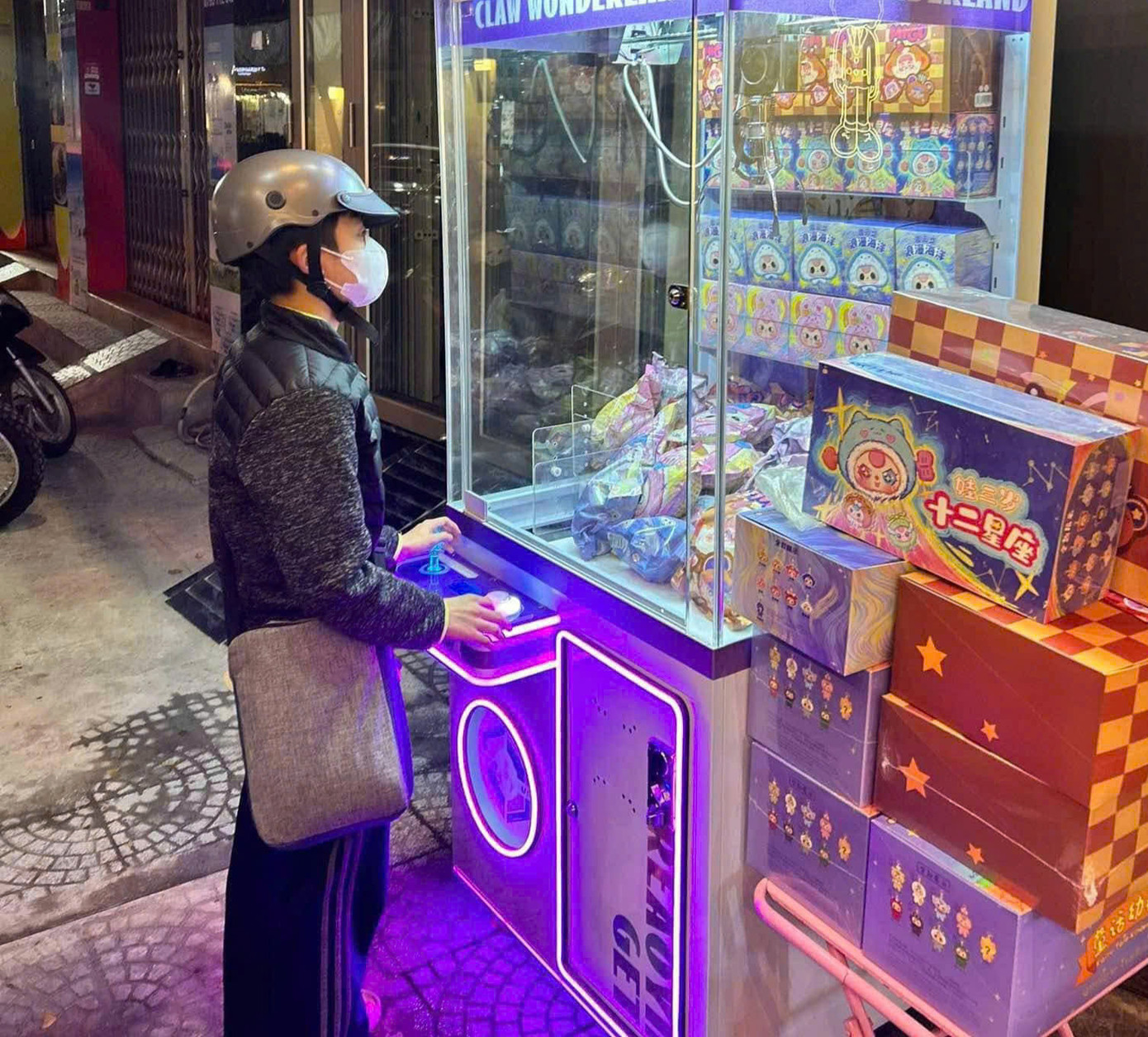 Một bạn trẻ mải mê gắp Baby Three tại một máy gắp trên đường. (Ảnh: Phương Anh)
