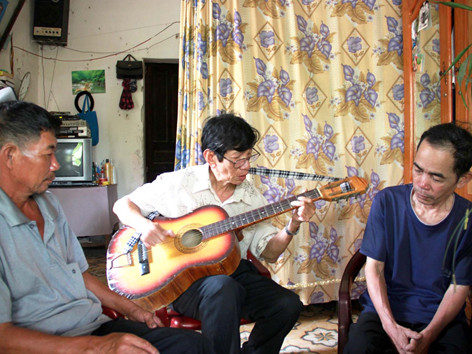 Ông Tiến chơi đàn cùng người dân trong xóm. Ảnh: nguyễn huy