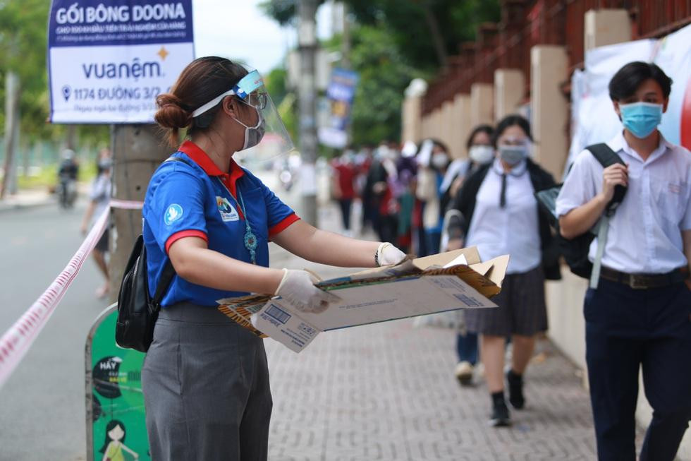 Tình nguyện viên dùng bìa giấy như biện pháp tránh nóng kịp thời cho các thí sinh - Ảnh: Dân Trí. Tình nguyện viên dùng bìa giấy như biện pháp tránh nóng kịp thời cho các thí sinh - Ảnh: Dân Trí.