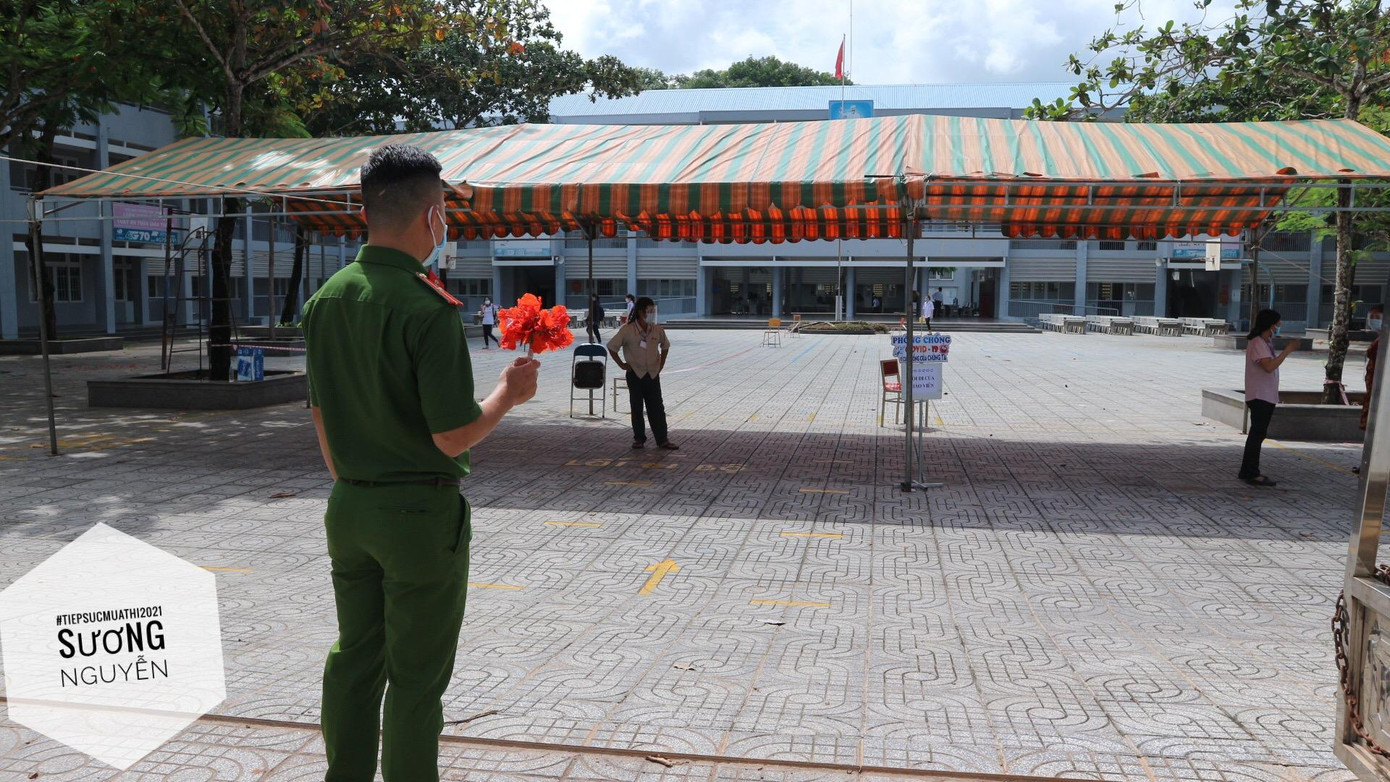 Anh công an chờ đợi các sĩ tử hoàn thành bài thi để trao nhánh hoa phượng đỏ rực. Ảnh: Sương Nguyễn. Anh công an chờ đợi các sĩ tử hoàn thành bài thi để trao nhánh hoa phượng đỏ rực. Ảnh: Sương Nguyễn.