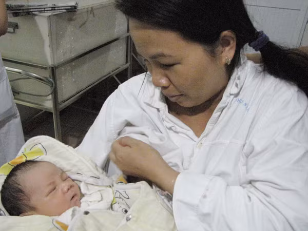Dù các bác sỹ cho biết cháu vừa uống sữa, nhưng chị Thơm vẫn vạch bầu sữa cho con bú. Ảnh: Lãng Phong