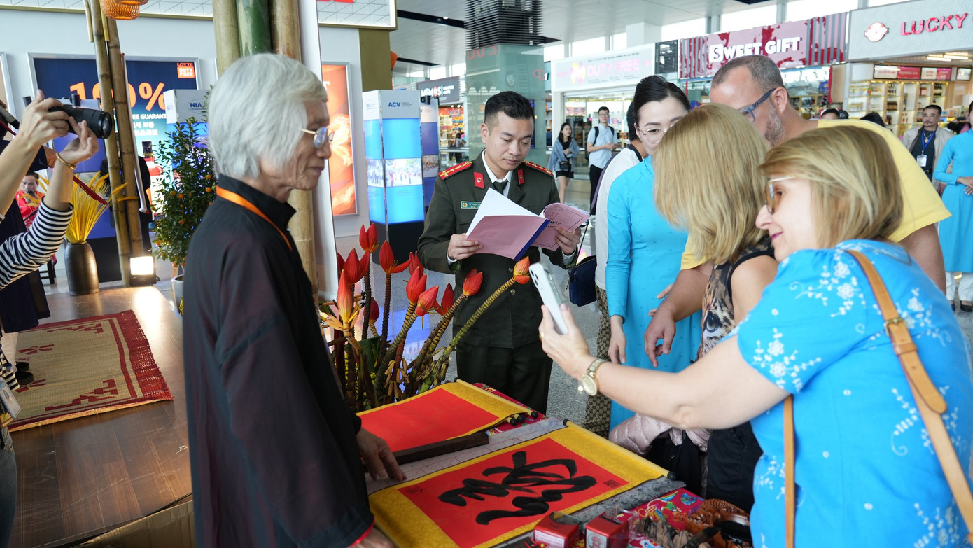 Các vị khách quốc tế hết sức ấn tượng với văn hoá tặng chữ đầu xuân, xin phép chụp ảnh cùng nghệ nhân. Điều này khiến hai thầy đồ Đỗ Tuấn Hải và Nguyễn Viết Sổ không khỏi tự hào. Ảnh: NIA.