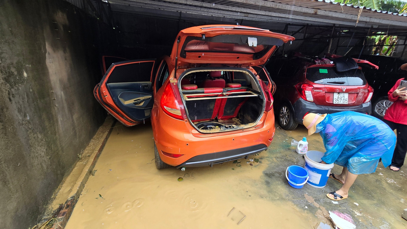 Người dân dọn dẹp, rửa xe ô tô bị ngập trong lũ. Ảnh: Hoàng Mạnh Thắng.