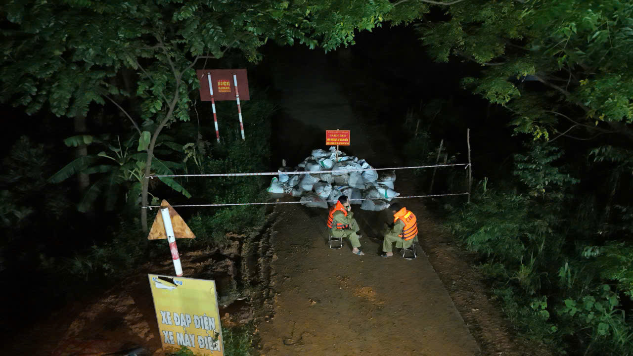 Hai chiến sĩ công an túc trực, canh giữ khu vực xảy ra sự cố vỡ đê sông Lô. Ảnh: Hoàng Mạnh Thắng.