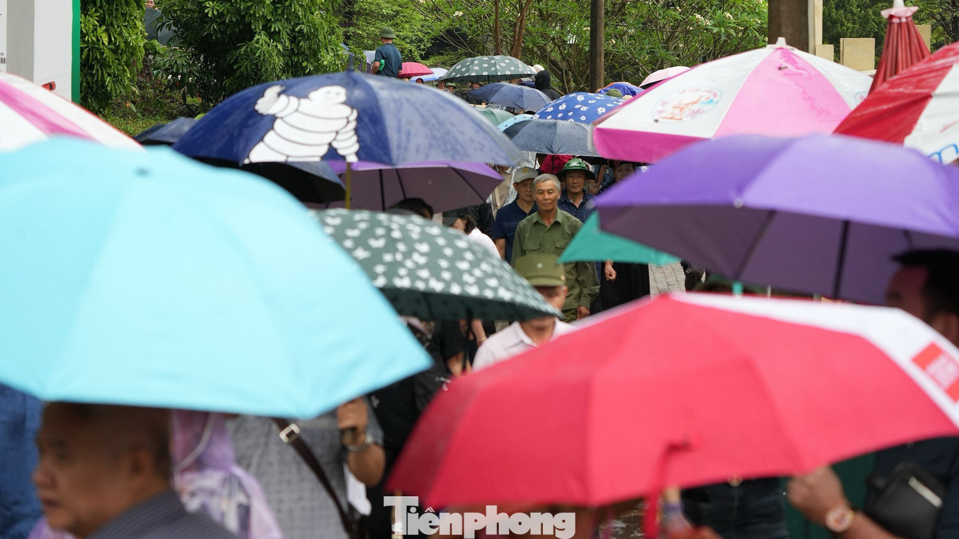 Rất nhiều người dân, du khách che ô, mặc áo mưa tham quan Khu di tích Đồi A1 sáng 6/5.