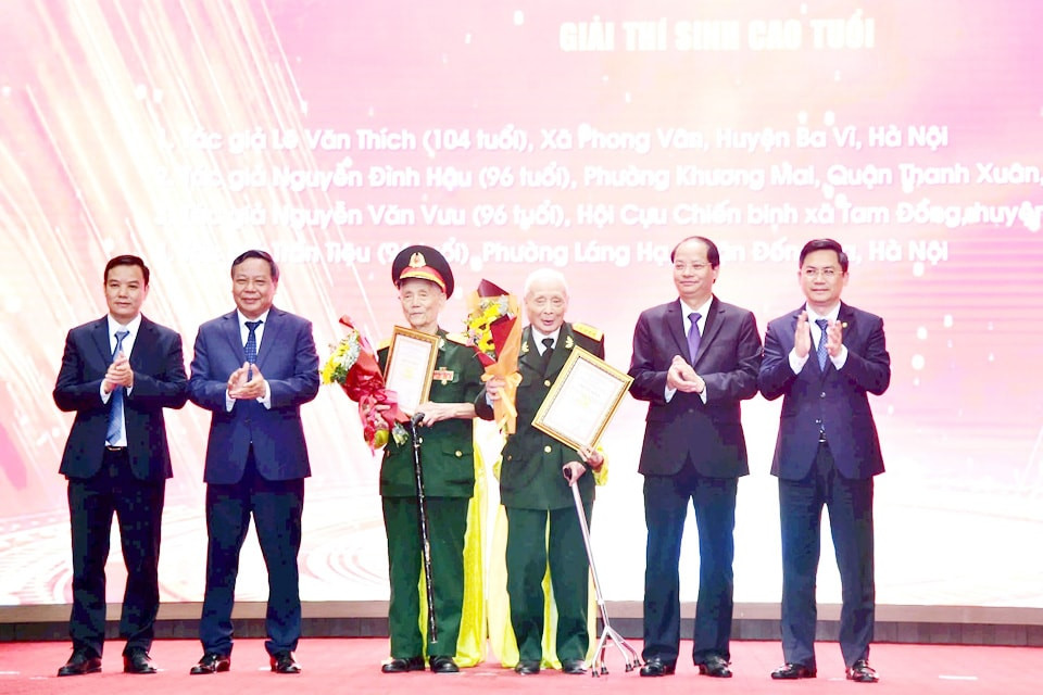 Phó Bí thư Thành ủy Hà Nội Nguyễn Văn Phong và thành phố chúc mừng hai tác giả cao tuổi nhất của cuộc thi. Ảnh: HNM.