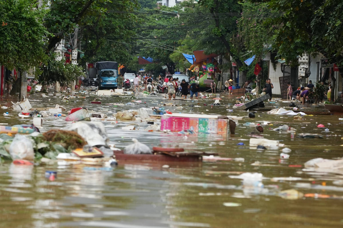 Dòng nước lũ cuốn theo nhiều rác thải, đồ đạc, vật dụng của người dân ra giữa phố. Ảnh: Hoàng Mạnh Thắng.