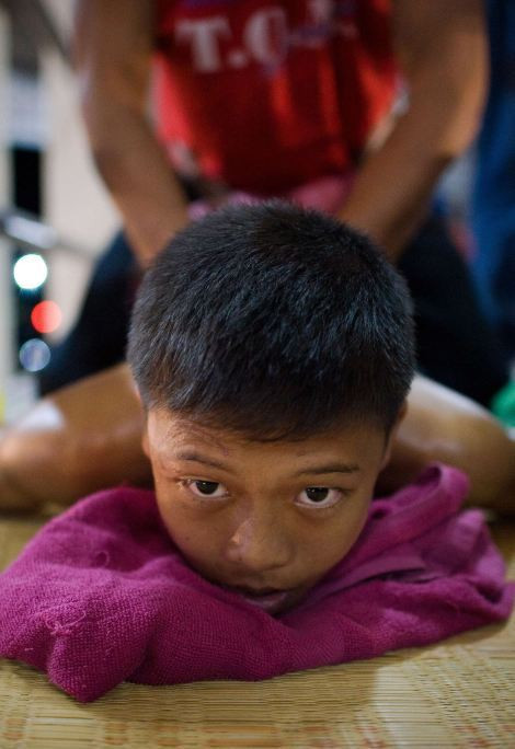 Cậu bé đang được huấn luyện viên đấm bóp trước khi thi đấu