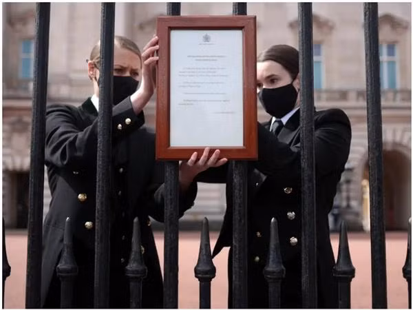Nhân viên của Cung điện Buckingham gắn thông báo lên cửa về việc Hoàng thân Philip qua đời. Ảnh: Hannah McKay/ Reuters.