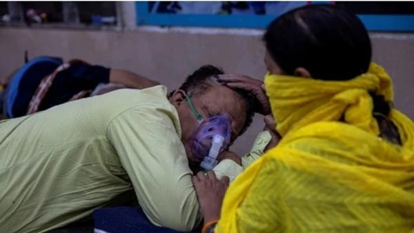 Một phụ nữ đang chăm chồng bị mắc COVID-19, trong khi người chồng đợi để được nhận vào bệnh viện Guru Teg Bahadur (New Delhi). Ảnh: Reuters.