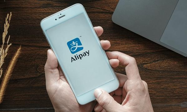 Huang mở ứng dụng Alipay trên máy của người yêu để chuyển tiền. Ảnh minh họa: Remitly. Huang mở ứng dụng Alipay trên máy của người yêu để chuyển tiền. Ảnh minh họa: Remitly.