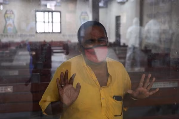 Một người đang áp vào cửa kính ở một khu hỏa táng ở New Delhi, nơi người nhà của ông, đã qua đời vì COVID-19, đang chờ được hỏa táng. Ảnh: Anushree Fadnavis/ Reuters.