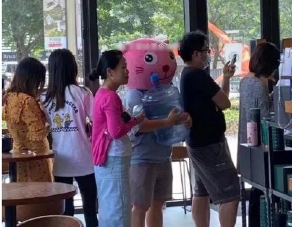 Có người (đội mặt nạ con mèo màu hồng) ôm cả bình nước gần 20 lít đi lấy cà phê miễn phí. Ảnh: Weibo.