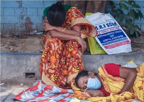 Người nhà của một bệnh nhân COVID-19 đang ngồi bên ngoài một bệnh viện công, nơi đang thiếu cả giường bệnh lẫn oxy. Ảnh: PTI.