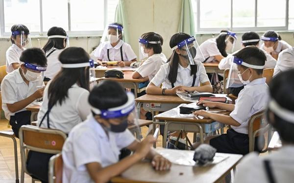 Học sinh ở một trường tiểu học tại Osaka đeo tấm chắn khi đi học (trước thời điểm học online); Ảnh: Kyodo. Học sinh ở một trường tiểu học tại Osaka đeo tấm chắn khi đi học (trước thời điểm học online); Ảnh: Kyodo.