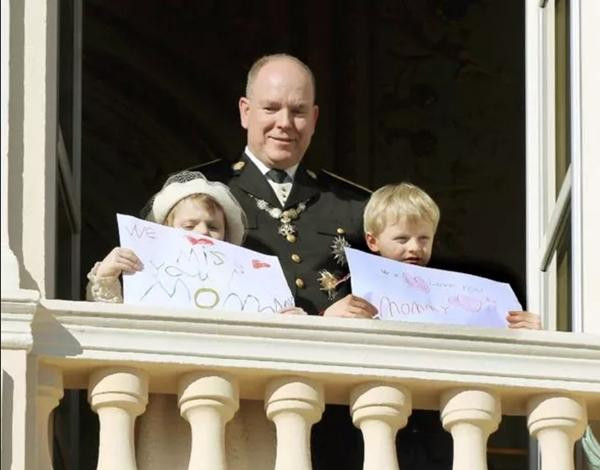 Hai con của bà Charlene đứng cùng với cha, tay cầm giấy thể hiện tình cảm với mẹ. Ảnh: PA. Hai con của bà Charlene đứng cùng với cha, tay cầm giấy thể hiện tình cảm với mẹ. Ảnh: PA.