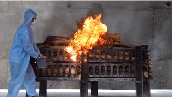 Một nhân viên tuyến đầu ở Ấn Độ đang đổ thêm chất lỏng dễ cháy vào một giàn thiêu để thiêu xác bệnh nhân COVID-19. Ảnh: Reuters.