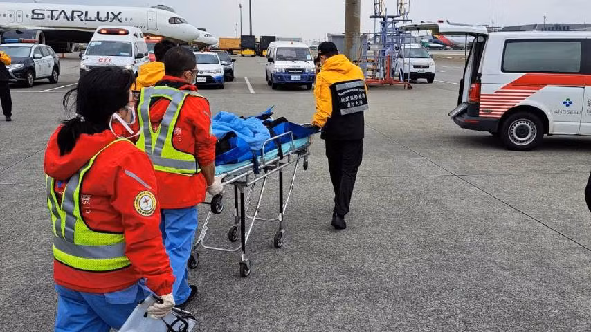 Hình ảnh hành khách của Vietnam Airlines được đưa đi cấp cứu sau khi máy bay hạ cánh khẩn cấp xuống sân bay Đào Viên. Ảnh: VNA.