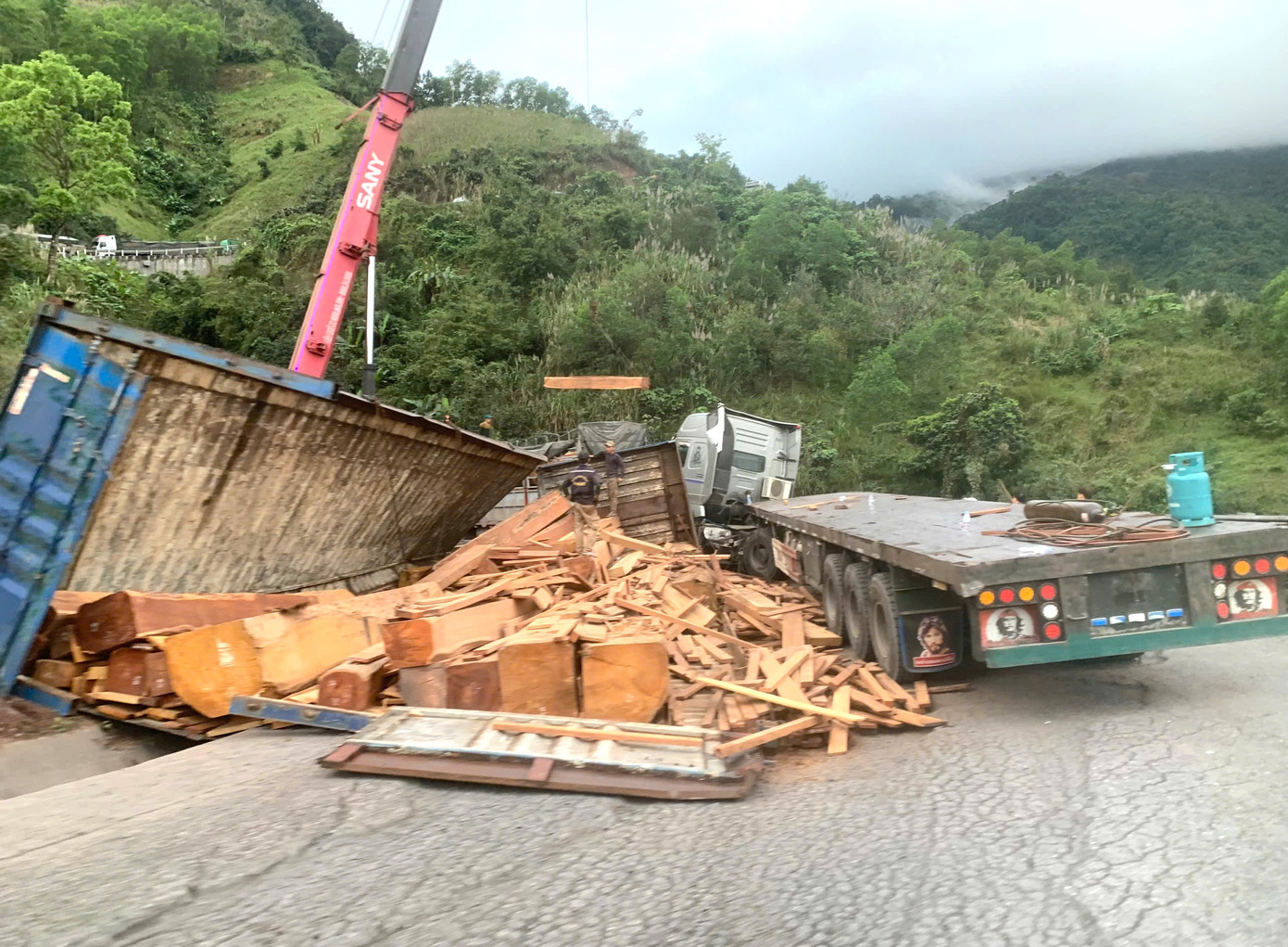 Các lực lượng chức năng khẩn trương cứu hộ xe chở gỗ bị lật để thông tuyến Quốc lộ 15D