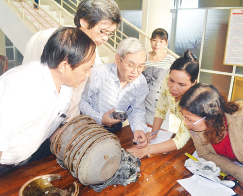 Chồng chậu gồm 11 chiếc chậu gốm tráng men nâu kết dính thành khối cùng san hô và tiền đồng có dấu hiệu bị cháy. Ảnh: Hiển Cừ